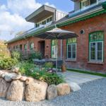 Red brick house with green trim, terrace, and garden with stone beds.