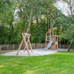 Wooden playground with slide and swing in the garden.