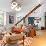 Living area with sofa, chairs, and wooden beam. Dining area with table and chairs.