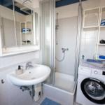 Badezimmer mit Dusche, Waschmaschine und Spiegelkabinett.
