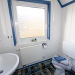 Badezimmer mit Waschbecken, Toilette und Fenster mit Jalousie.