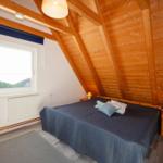 Schlafzimmer mit Holzwand, Bett und Fenster