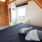 Schlafzimmer mit Dachschrägen, Bett, Kleiderständer und Fenster.