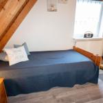 Schlafzimmer mit Dachschrägen, Bett, Nachttisch, Fernseher und Fenster.