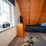 Schlafzimmer mit Holzdecke, Bett, Schrank und TV auf Kommode.