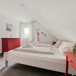 Schlafzimmer mit Doppelbett, rotem Schrank und Fenster.