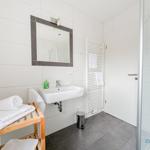 Badezimmer mit Waschbecken, Spiegel, Dusche und Handtuchhalter.