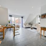 Wohn- und Essbereich mit Sofa, Tisch und Stühlen sowie großem Fenster.