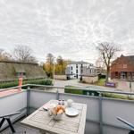 Terrasse mit Tisch und Stühlen. Blick auf Dorf mit Kirche und traditionellem Haus.