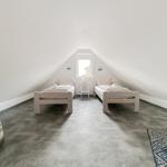 Zwei Einzelbetten stehen unter einem Dachbodenfenster mit einem Nachttisch dazwischen.