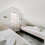 Zwei Betten mit Bettwäsche und ein Fenster in einem Dachzimmer.