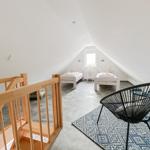 Zimmer mit zwei Betten, Treppe und Sitzgelegenheit im Dachgeschoss.