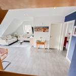 Wohnung mit Wohn- und Essbereich, Sofa, Tisch und Stühle. Wandbild und Tür sichtbar.