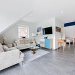 Wohnzimmer mit Sofa, Fernseher und Blick auf Schlafzimmer.