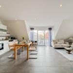 Offener Raum mit Küche, Essbereich und Wohnbereich. Balkon mit Sitzgelegenheit.