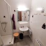 Badezimmer mit Dusche, Waschbecken und Spiegel.