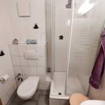 Badezimmer mit Dusche, Toilette und Waschbecken. Wanddekoration mit Steinen und einem Schild.