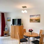 Wohnzimmer mit Essbereich, TV und Balkontür.