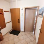 Eingangsbereich mit Tür, Wandgarderobe und Bodenfliesen.