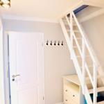 Hausgang mit weißen Treppe, Kleiderhaken und Schrank. Holzboden und weiße Tür.