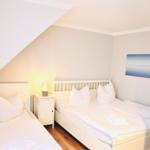 Zimmer mit zwei Betten, Nachttisch und Wandbild.