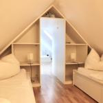 Zwei Betten unter Dachschrägen mit Nachttischen und Schränken