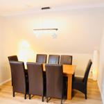 Esszimmer mit Holztisch, sechs Stühlen und Deckenleuchte.