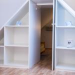 Zimmer mit Dachschränken und kleinem Bett im Hintergrund.