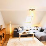 Wohnzimmer mit grauem Sofa, Holzmöbeln und Dachfenster.