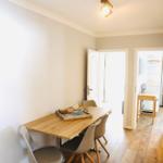 Essbereich mit Holztisch und Stühlen. Durchgang zu Schlafzimmer und Bad.