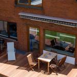 Holzterrasse mit Sitzgruppe und Strandkorb vor Backsteinhaus.