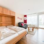 Schlafzimmer mit Bett, Sofa und Balkonzugang.