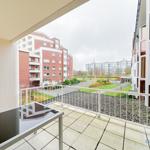 Terrasse mit Tisch und Blick auf Wohnkomplex und Grünflächen.
