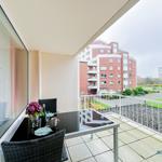 Terrasse mit Tisch und Stühlen, Blick auf Wohngebäude und Grünfläche.
