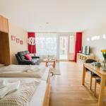 Zwei Betten, Sofa, Esstisch und Balkon mit roten Vorhängen.