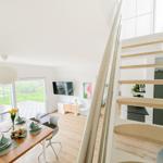 Essbereich mit Tisch, Stühlen und Blick auf Terrasse. Treppenhaus führt zur oberen Etage.