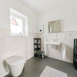 Badezimmer mit Toilette, Waschbecken und Fenster.