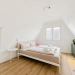 Schlafzimmer mit Doppelbett, Fenster und Holzboden.