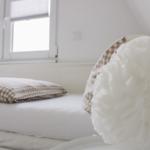 Schlafzimmer mit Bett, Fenster und dekorativer Deckenlampe.