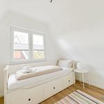 Schlafzimmer mit Bett, Fenster und kleinem Tisch.