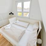 Schlafzimmer mit zwei Betten und Fenster. Holzfußboden und weißer Schrank.