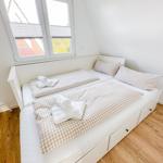 Zimmer mit Schlafcouch, Fenster und Holzboden.