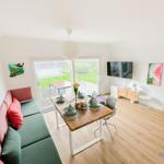 Wohn- und Essbereich mit Sofa, Tisch und TV. Durchgang zur Schlafzimmer.