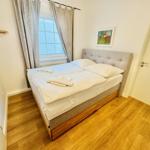 Schlafzimmer mit Doppelbett, Holzboden und Fenster mit Vorhängen.