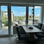 Essbereich mit Tisch und Stühlen. Große Fenster mit Blick auf Balkon und Stadt.