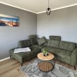Ein Wohnzimmer mit grünem Sofa, runden Tisch und Wandbild.