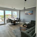 Wohn- und Essbereich mit Balkon, Sofa, Tisch und Fernseher.