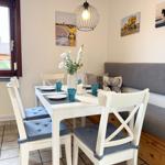 Dining area with table, chairs, and sofa. Wall art and window view.