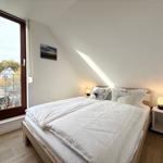 Bedroom with sloped ceiling, bed, nightstands, and window with view.