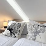 The bed has pillows and a duvet cover. A lamp is on a bedside table.